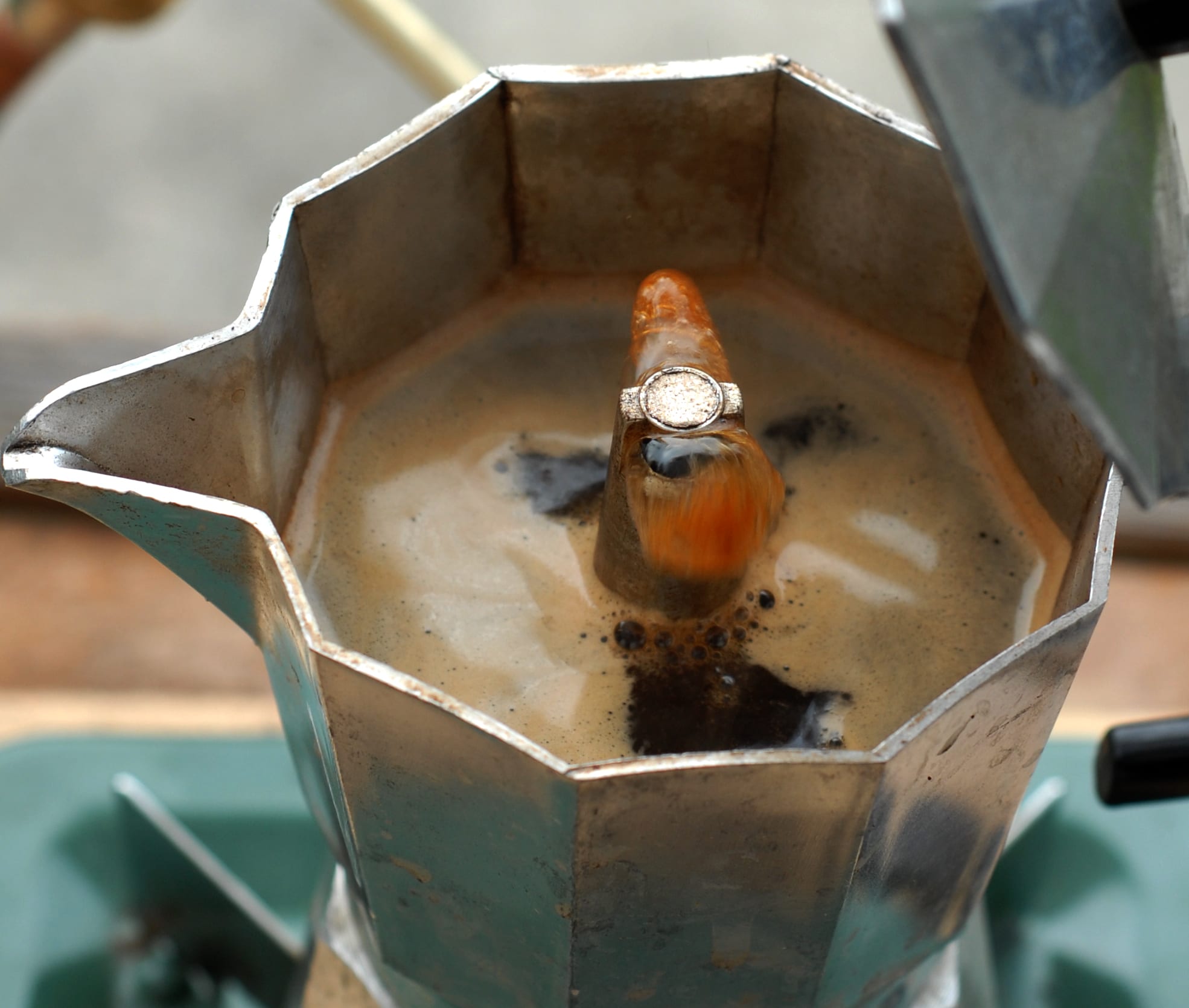 Coffee emerging from the column of a stovetop moka pot.